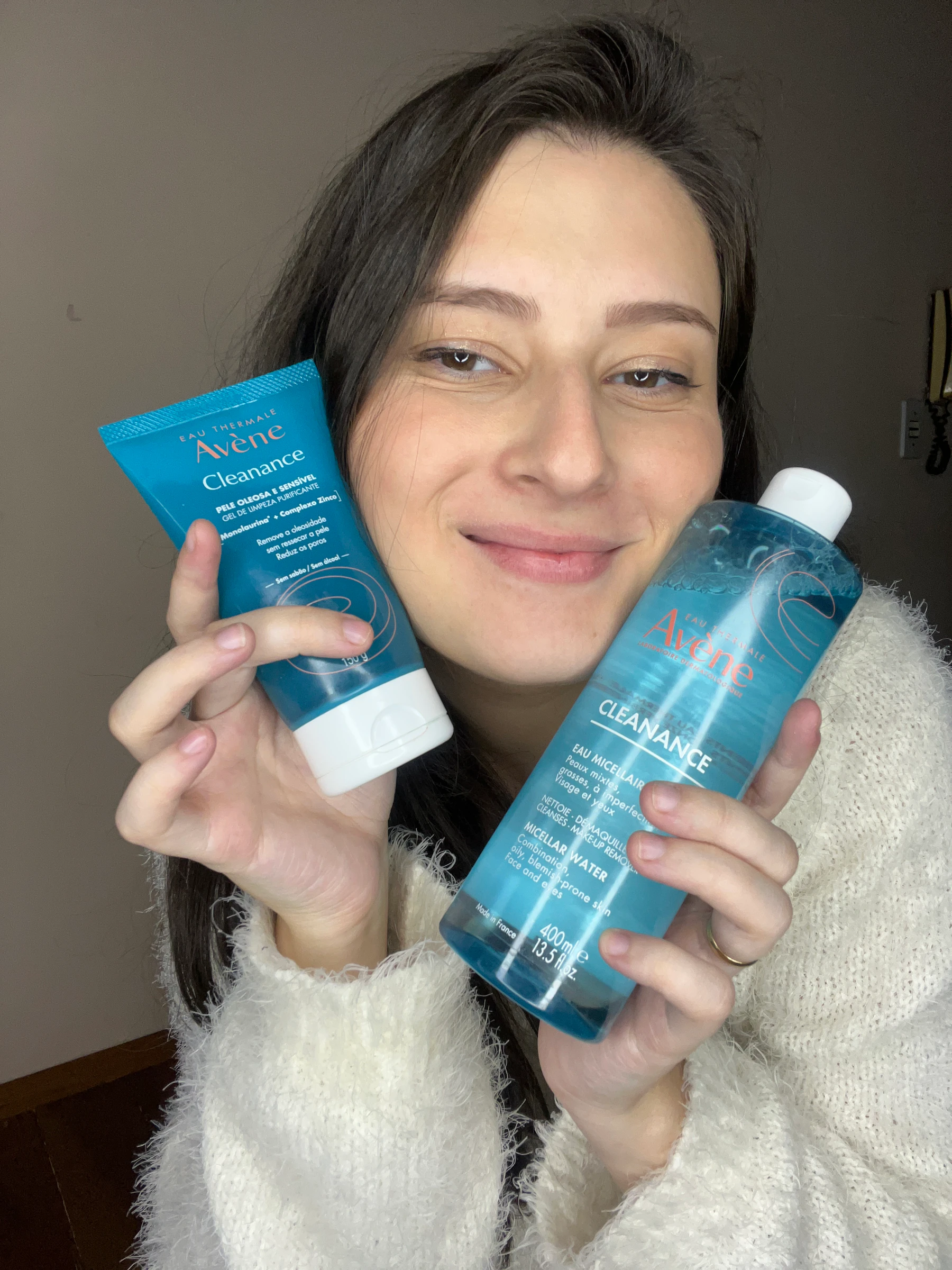 Gabi sorri com dois produtos Avène Cleanance próximos ao rosto.