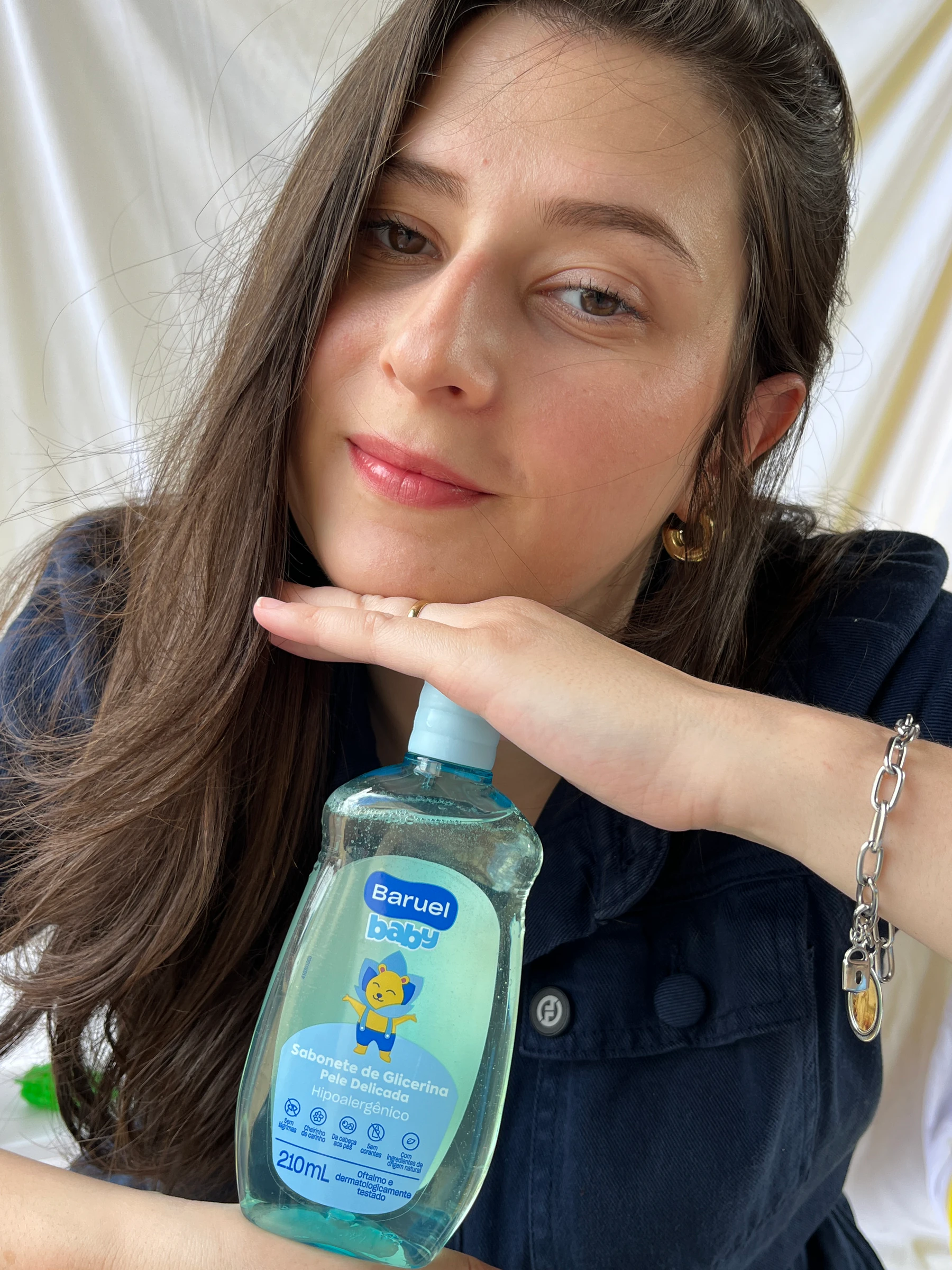 Gabi segura produtos Baruel Baby em um retrato próximo.
