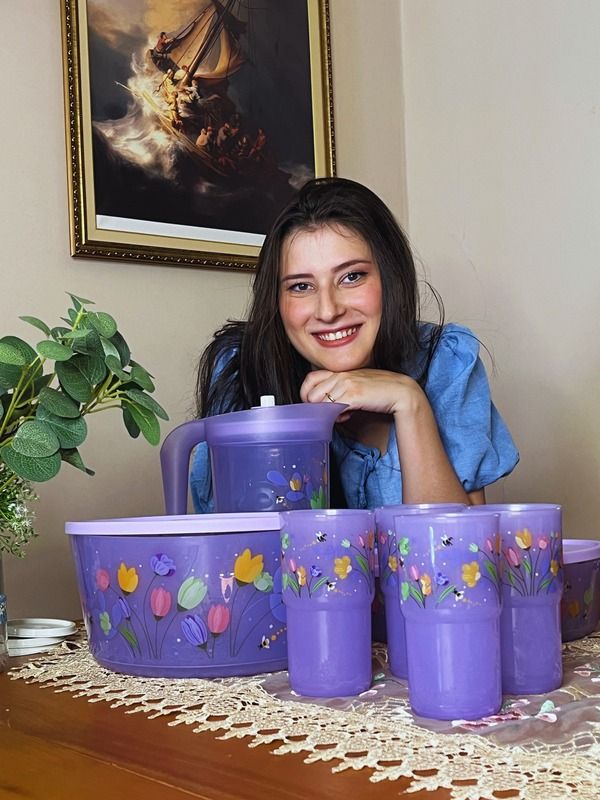 Gabi sorri atrás de uma coleção de recipientes roxos Tupperware.